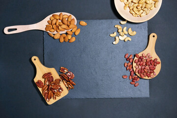 nuts on a dark table. Pecans, Cashews, almonds, peanuts. Top view with space to copy.