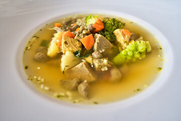 Ein weißer Teller Gemüsesuppe, Hühnersuppe mit Karotten, Leberknödel und Bio Gemüse, Hausrezept nach Oma in der Erkältungszeit