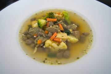 Ein weißer Teller Gemüsesuppe, Hühnersuppe mit Karotten, Leberknödel und Bio Gemüse, Speisekarte