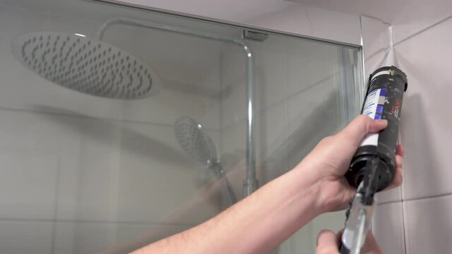 4k video of a man insulating a shower screen gasket with silicone
