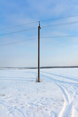 Electric pole with wires in a snowy field