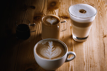 Cafe latte macchiato americano with layers of coffee in a glass coffee cup. Cup of coffee is on a wooden background, top view. Dark background. Low key. Selective focus