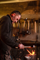 Blacksmith working in the forge. Manufacture of parts  from molten metal, using the hammer and anvil.