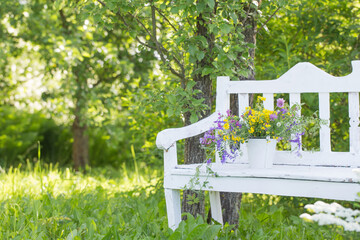 wild flowers on white wooden bench in summer garden