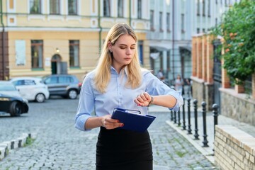 Young business woman in the city looking at her wristwatch
