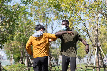 Two Sport man friends wearing surgical face mask new normal greeting. Elbow bump. New normal greeting to avoid the spread of coronavirus