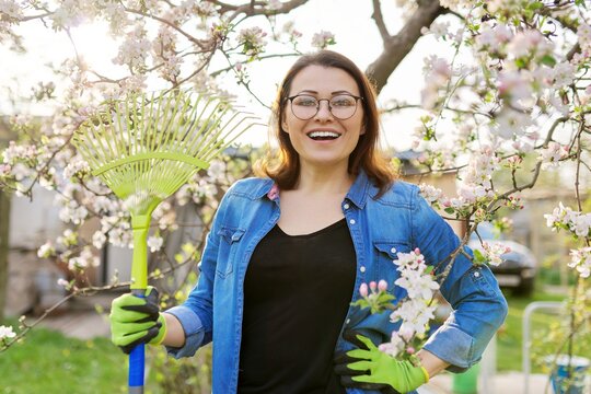 Spring gardening, portrait of mature smiling woman with rake looking at camera
