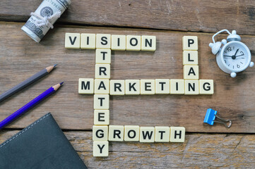 Scrabble letters with text VISION, STRATEGY, MARKETING, GROWTH and PLAN over wooden background. 