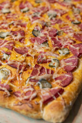 Top view hot salami pizza with cheese and bell pepper decorated with cucumbers, gherkins and chili pepper