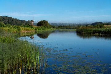 State museum-reserve of Alexander Pushkin. Beautiful russian landscape with an old windmill on the bank of the Sorot river. July 2020.