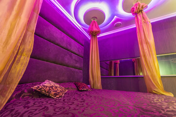 Romantic lounge, violet light color. Oriental style and a baldachin.