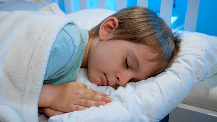 Portrait of calm little 5 years old boy sleeping and having good dreams at night. Children bedtime