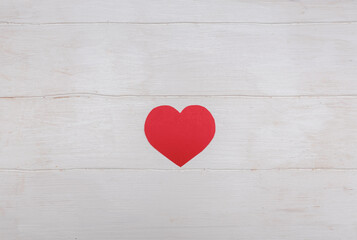 Red heart. On a white wooden background. Minimalism. For the design and writing of text.