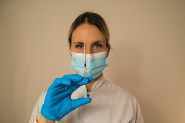 Close-up of female nurse or doctor with mask and covid19 coronavirus vaccine