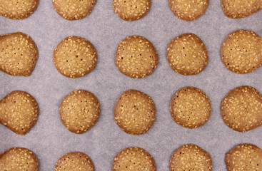 Background from round cookies with sesame seeds. Cookies, do it yourself. Baking on baking paper