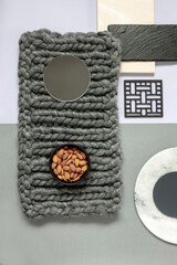 Modern trendy wellness concept with almond, natural stones plates and knitting homemade. Close up, top view on neutrals tones paper background