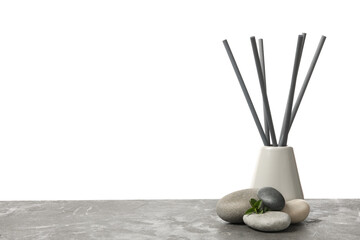 Spa stones, green branch and reed air freshener on grey table against white background. Space for text