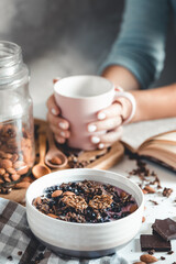 Healthy breakfast, muesli with berries and orange juice served on glass table and books. manicure