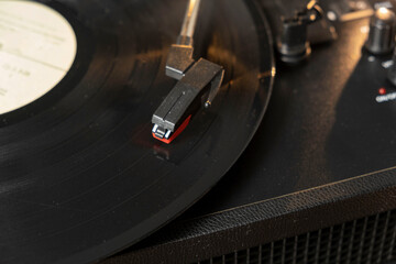 Vintage old retro vinyl electronic record player with black record and cartridge needle installed close up