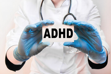 The doctor's blue - gloved hands show the word ADHD - . a gloved hand on a white background. Medical concept. the medicine