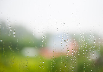 raindrops on window during summer rain (houses on the background)