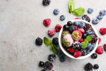 Mix of different frozen berries on grey table, flat lay. Space for text