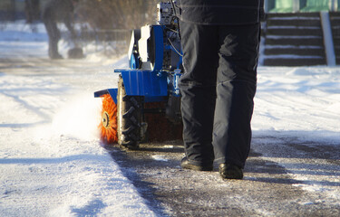 a man works with a snow blower at a winter day