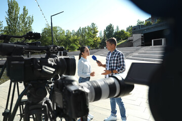 Professional journalist interviewing young woman on city street