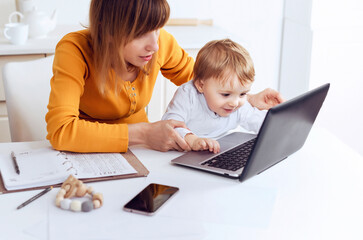 Mom and baby with laptop computer working from home.