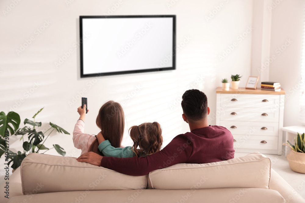 Wall mural family watching tv on sofa at home, back view