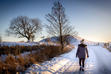 woman walking along snow covered road