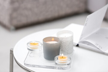 Burning candles in beautiful holders on white table indoors