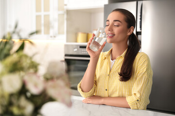 Young woman drinking pure water from glass indoors, closeup