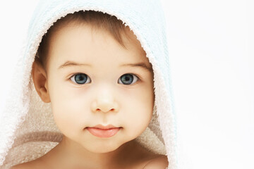 Cute infant boy with beautiful eyes wrapped into hooded towel after a bathing