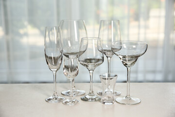 Different elegant empty glasses on grey table indoors