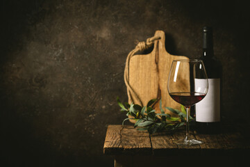 Glass of red wine with bottle against rustic dark wooden background
