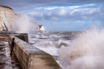 young boy and waves smashing against the defences