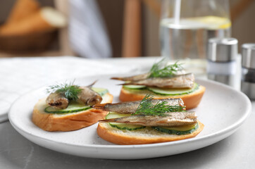 Delicious sandwiches with sprats, cucumbers and dill on light table
