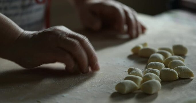 old woman's hand making gnocchi, footage with natural light and shadows from the window