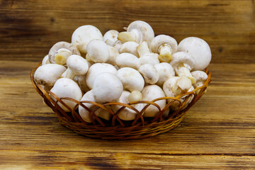 Fresh champignon mushrooms in wicker basket on the wooden table