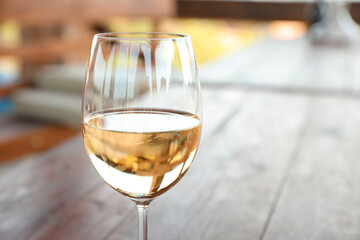 Glass of delicious white wine on blurred background, closeup. Space for text