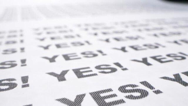 text background. extremely close-up, detailed. typing the word yes with an exclamation mark printed on white paper in black