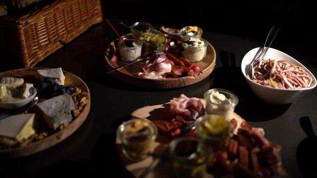 Composition of dishes. Slicing of smoked meats and various sori of cheese on a dark background.