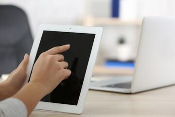 Young woman using new modern tablet in office, closeup. Space for text