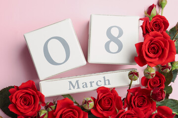 Wooden block calendar with date 8th of March and roses on pink background, flat lay. International Women's Day