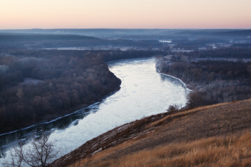 The first frost on the river in autumn. The trees on the shore are covered with hoarfrost.