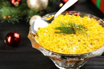 Traditional russian salad Mimosa and festive decor on dark wooden table, closeup