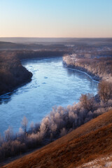 The first frost on the river in autumn. The trees on the shore are covered with hoarfrost.