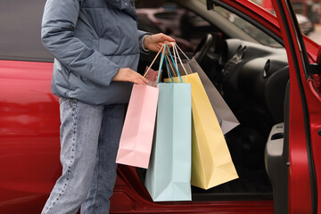 Woman with shopping bags near her car outdoors, closeup