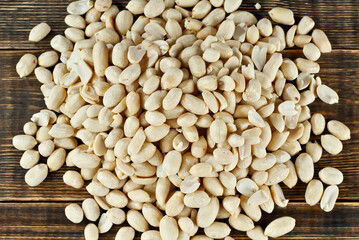 Peeled peanuts on a brown board. Texture of nuts on a wooden old table. Lots of nuts in a pile.